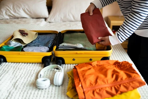 Woman packing cosmetics, clothes, and accessories into luggage.